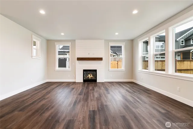 an empty room with wooden floor fireplace and windows