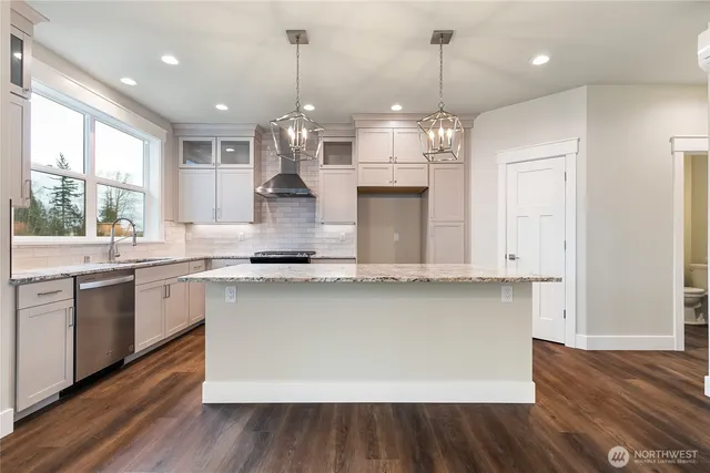 a kitchen with kitchen island granite countertop a stove a sink a center island and wooden floor