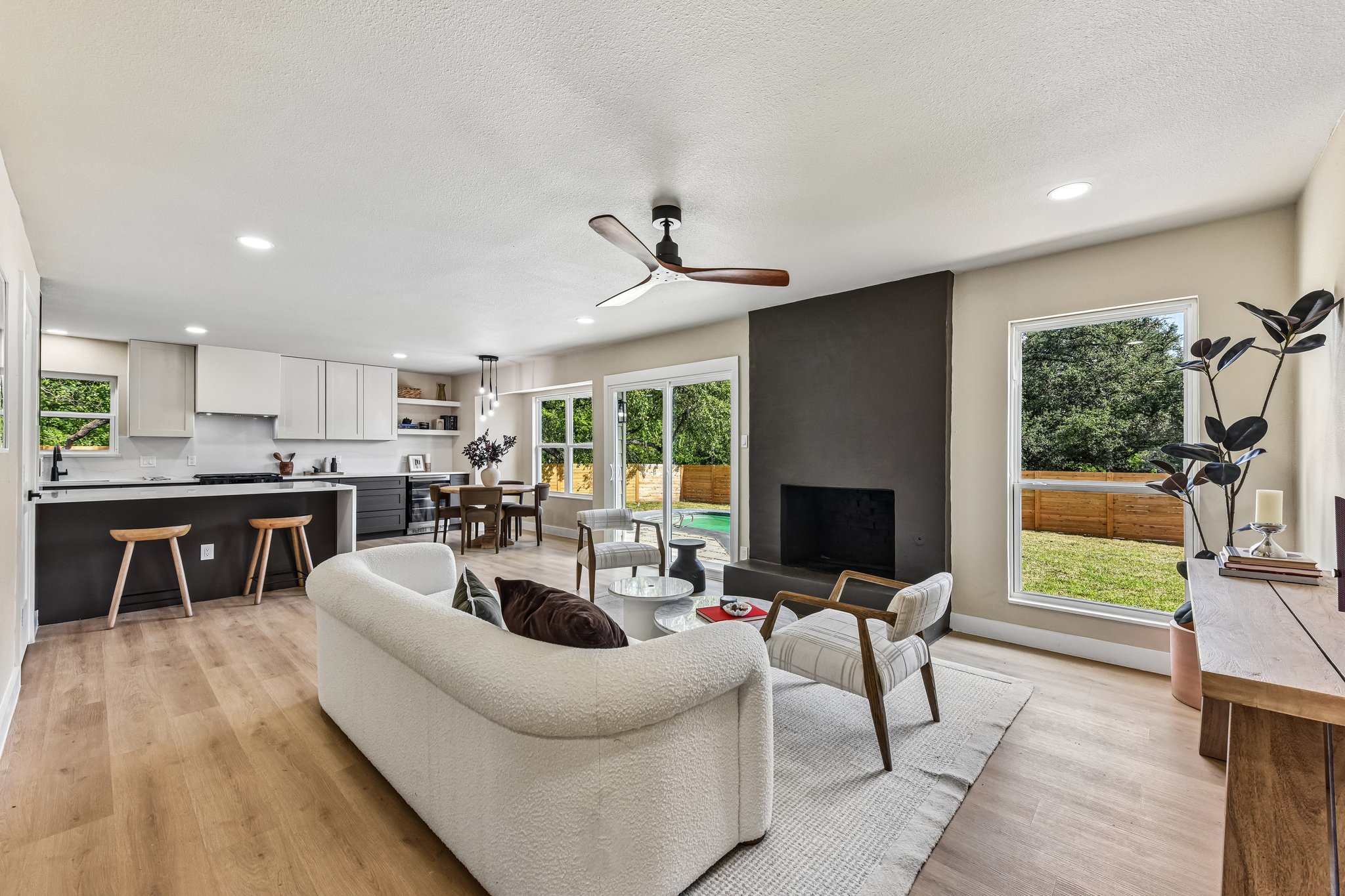 7523 Glenhill Road Austin, TX 78752 - Photo 15 of 38 An open-concept living area flows into a modern kitchen, anchored by a sleek fireplace and overlooking a private outdoor pool.