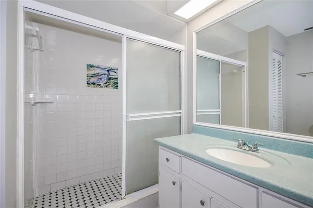 a bathroom with a granite countertop sink a mirror a shower and a vanity