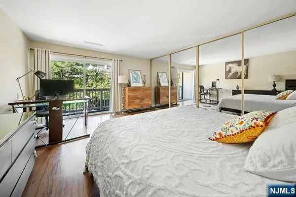 a bedroom with a bed a desk and chair with wooden floor