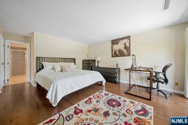 1225 River Road, Unit 6A Edgewater, NJ 07020 - Photo 18 of 30 a bedroom with a bed a desk and chair with wooden floor