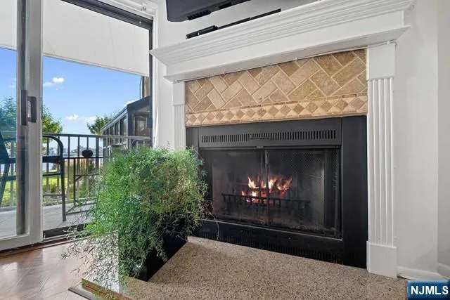 a living room with a fireplace a flat screen tv and a floor to ceiling window