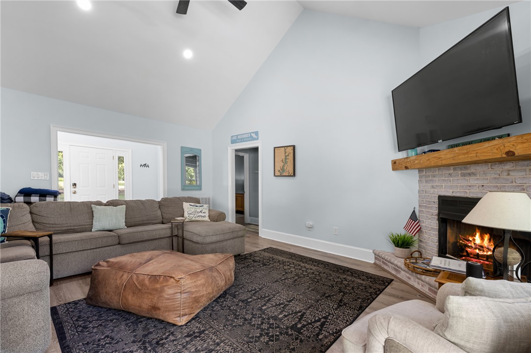 206 Petty Road Seneca, SC 29672 - Photo 8 of 47 An inviting gathering space features lofty vaulted ceilings and a cozy brick fireplace, ready for relaxation.