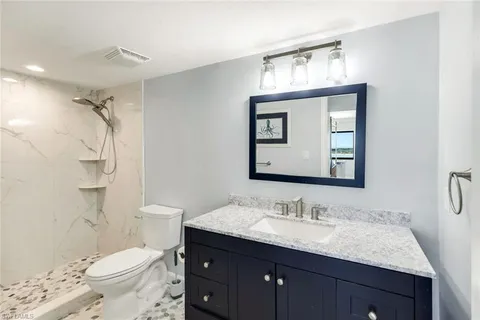 a bathroom with a granite countertop sink toilet and shower