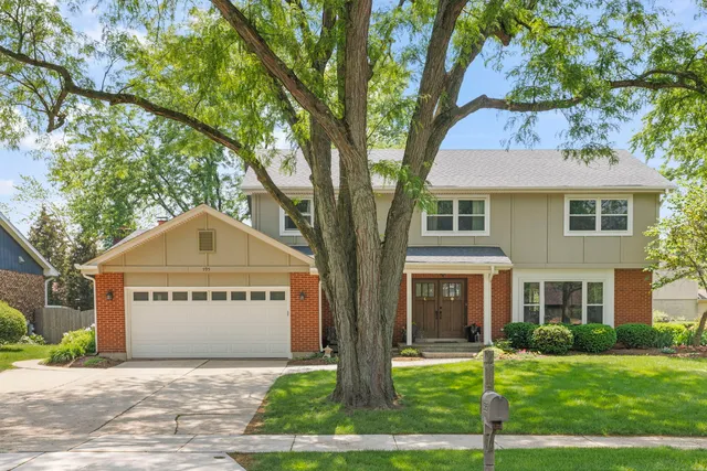 a view of a brick house with a yard and large trees