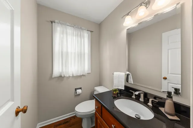 a bathroom with a granite countertop sink toilet a mirror and a window