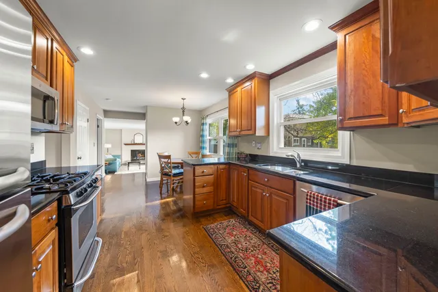 a kitchen with stainless steel appliances granite countertop sink stove and wooden cabinets