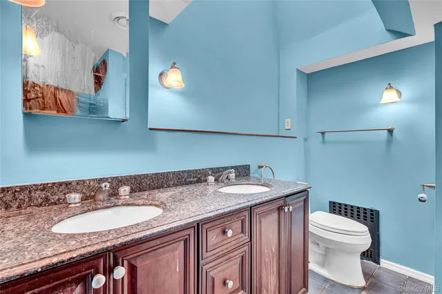 a bathroom with a granite countertop sink and a toilet