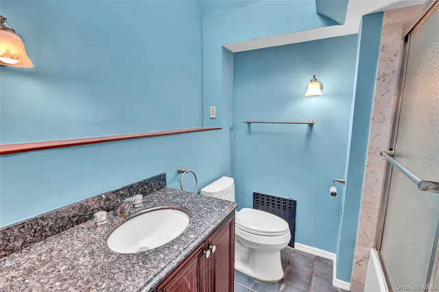 a bathroom with a granite countertop sink toilet and mirror