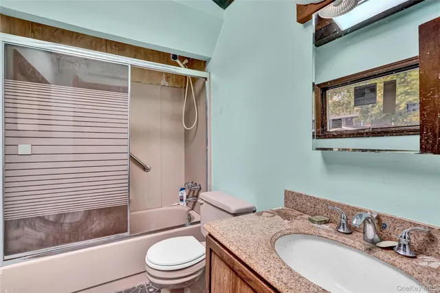 a bathroom with a granite countertop sink toilet and shower