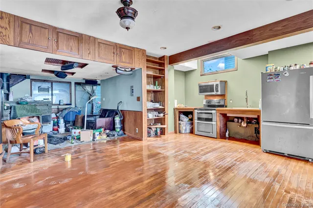 a kitchen with stainless steel appliances kitchen island granite countertop a refrigerator a stove a sink dishwasher and white cabinets with wooden floor