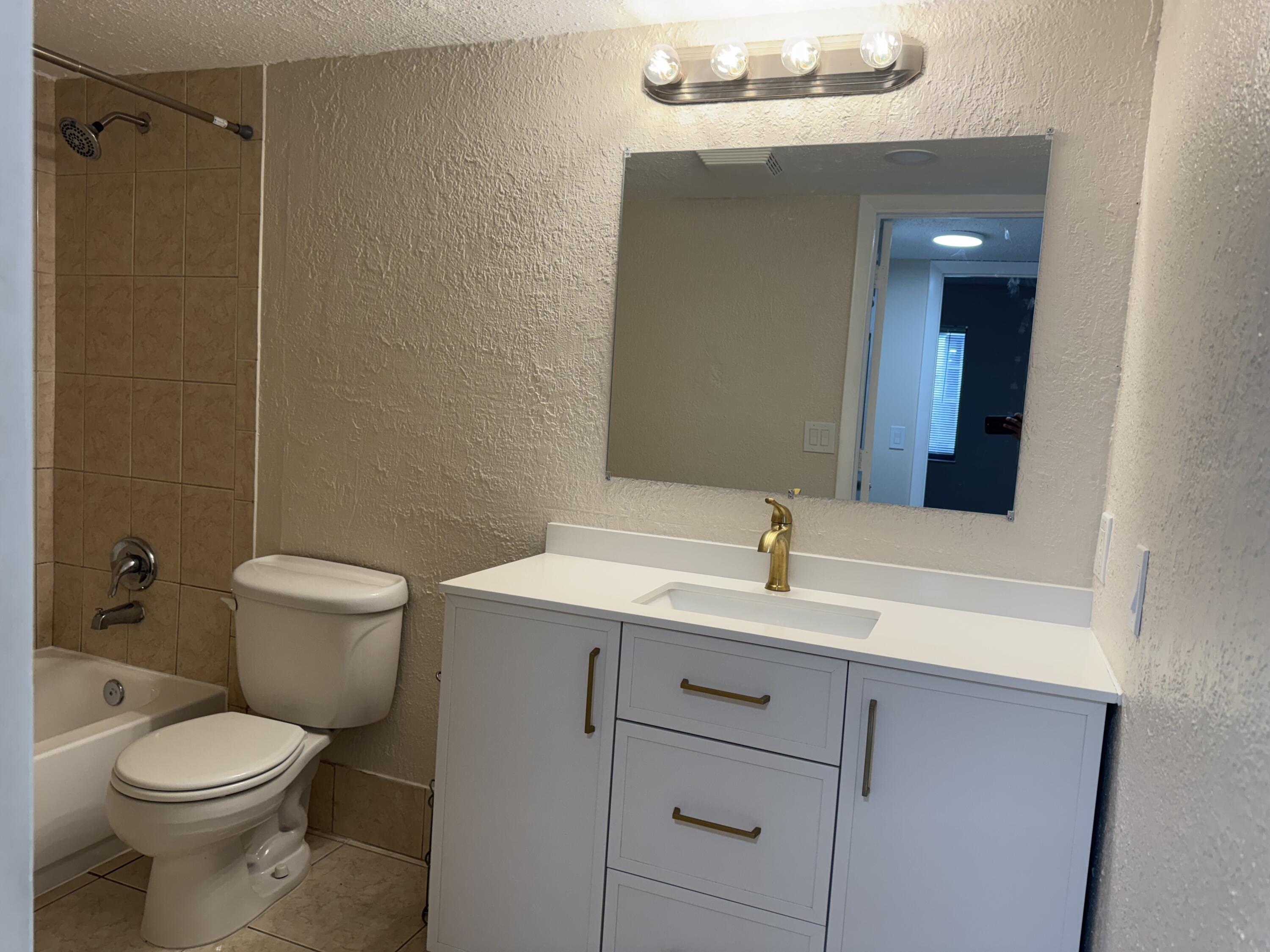 3710 North Pine Island Road, Unit 122 Sunrise, FL 33351 - Photo 27 of 39 a bathroom with a toilet sink and mirror