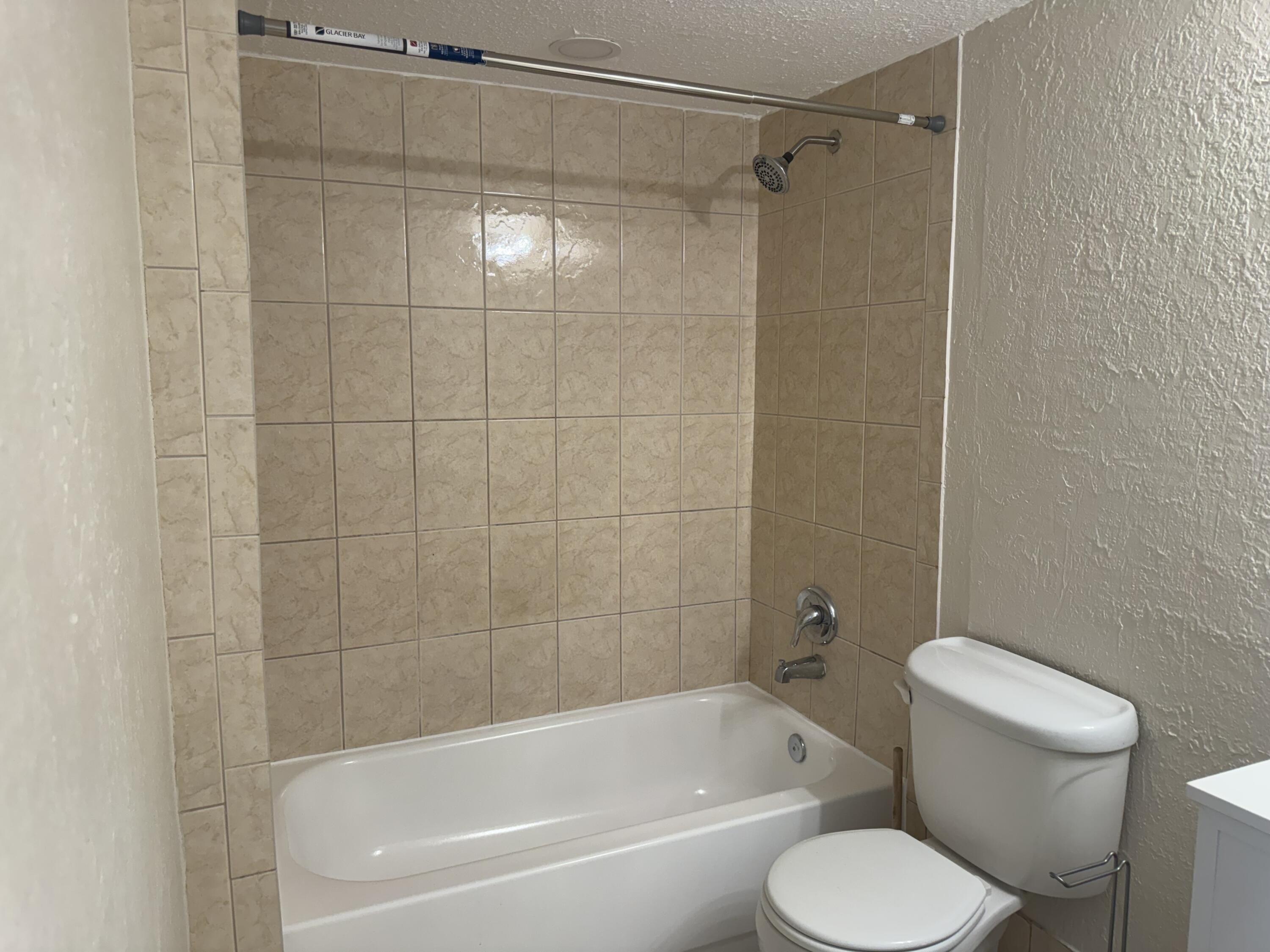 3710 North Pine Island Road, Unit 122 Sunrise, FL 33351 - Photo 28 of 39 a white toilet and tub sitting next to a bathroom sink