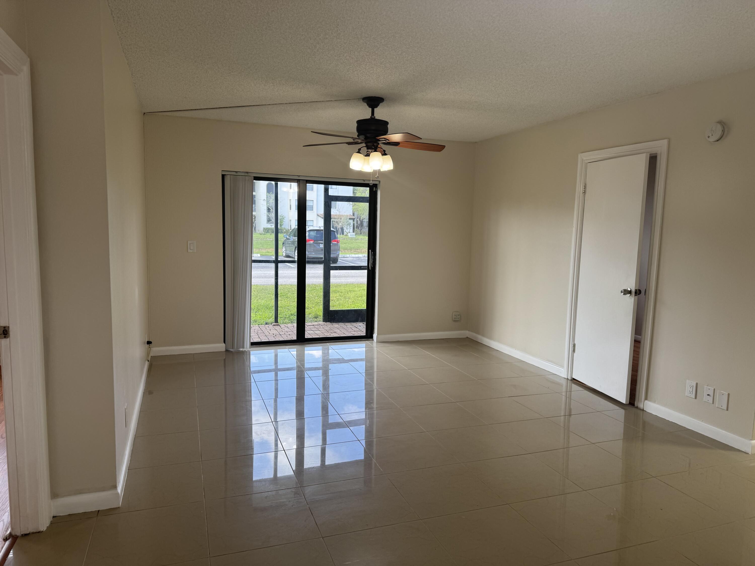 3710 North Pine Island Road, Unit 122 Sunrise, FL 33351 - Photo 3 of 39 an empty room with windows and chandelier fan