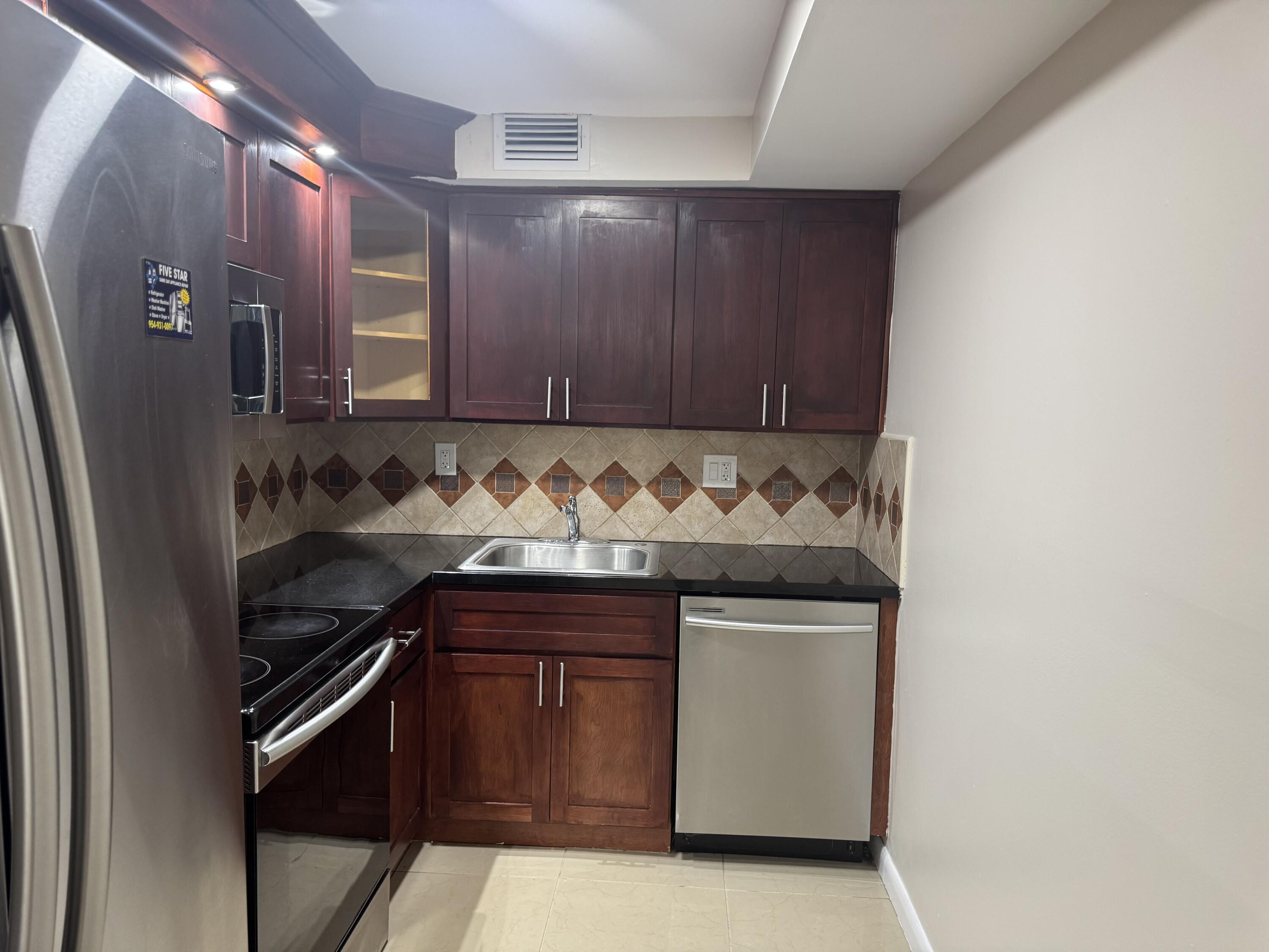 3710 North Pine Island Road, Unit 122 Sunrise, FL 33351 - Photo 7 of 39 a utility room with granite countertop white cabinets and stainless steel appliances