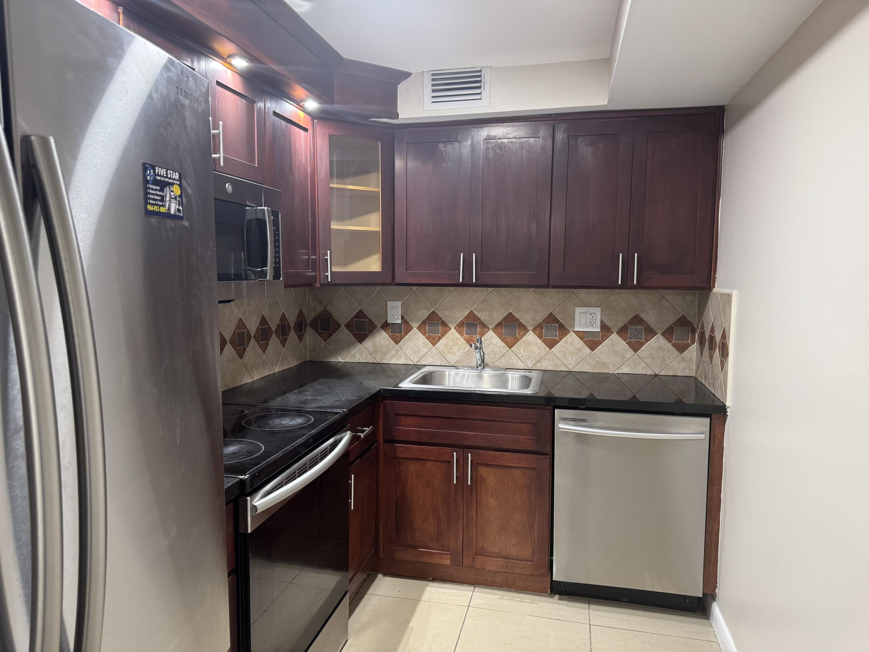 3710 North Pine Island Road, Unit 122 Sunrise, FL 33351 - Photo 8 of 39 a kitchen with granite countertop wood cabinets and stainless steel appliances