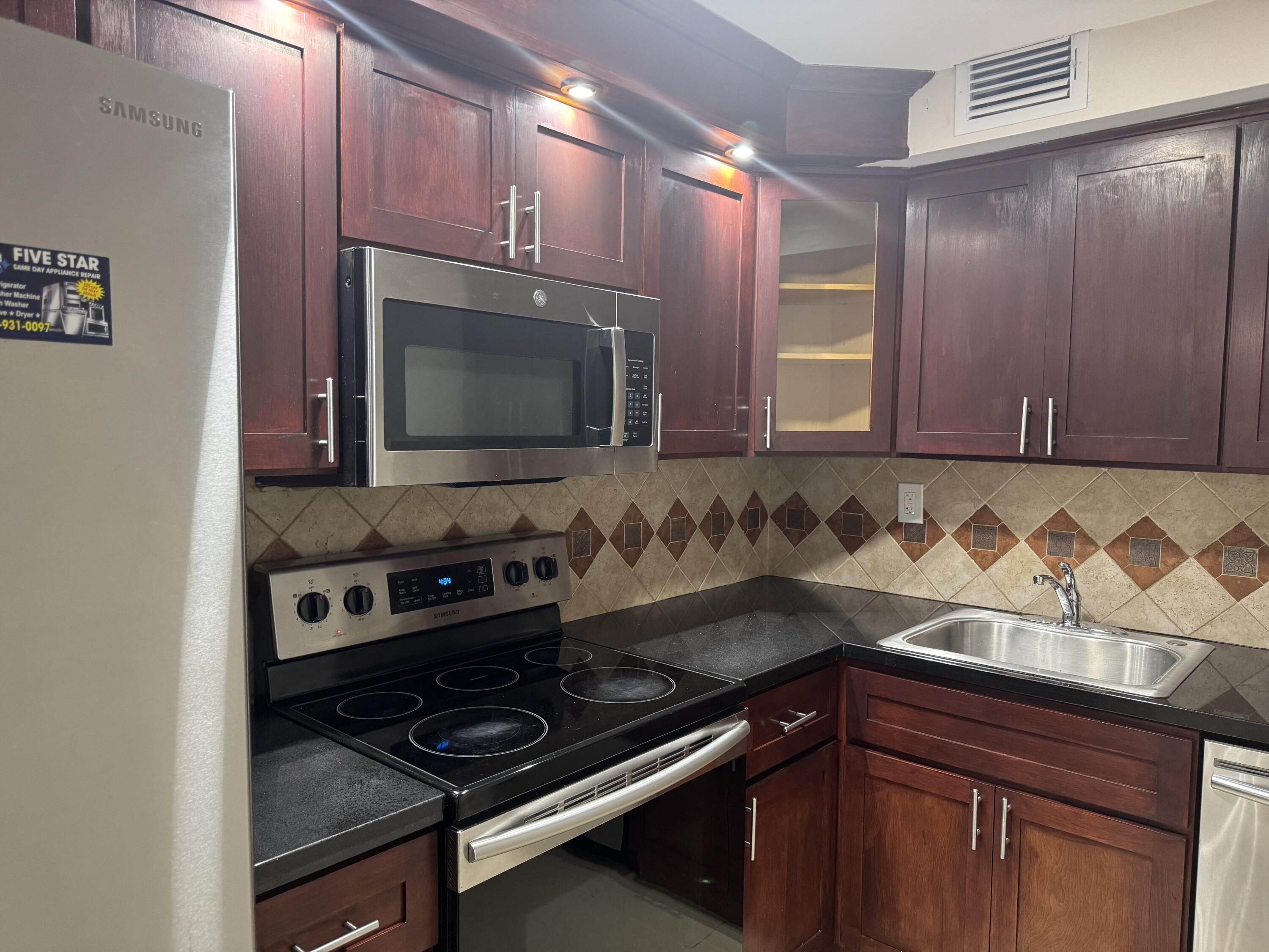 3710 North Pine Island Road, Unit 122 Sunrise, FL 33351 - Photo 10 of 39 a kitchen with granite countertop cabinets and black appliances
