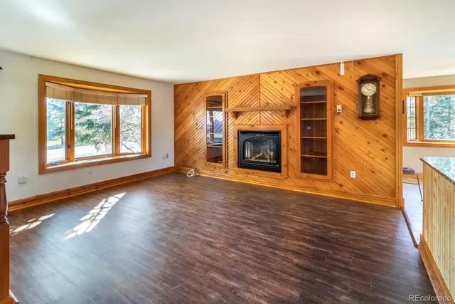 an empty room with wooden floor fireplace and windows