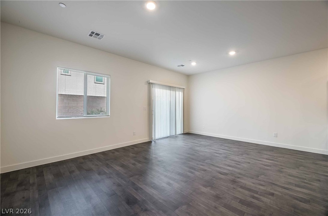 12749 Epperly Street Henderson, NV 89044 - Photo 3 of 22 A spacious living area with resilient plank flooring and natural light from a large window and glass sliding door.