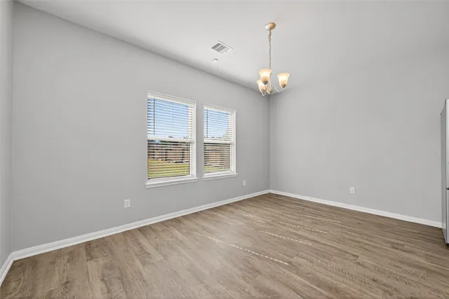 an empty room with wooden floor ceiling fan and window