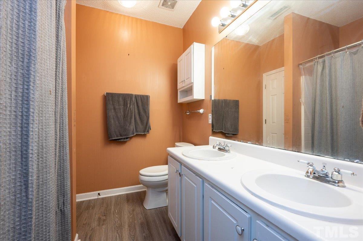 8616 Neuse Stone Drive Raleigh, NC 27616 - Photo 18 of 24 a bathroom with a double vanity sink toilet and a mirror