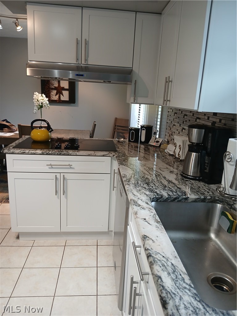 13872 Patch Road Burton, OH 44021 - Photo 19 of 33 Kitchen with range hood, whirlpool cooktop and adjacent new wall oven tasteful backsplash and granite counters, white cabinetry, and light tile floors. All stainless steel appliances.