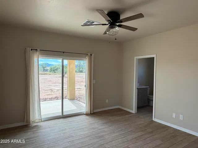 an empty room with wooden floor fan and windows