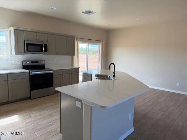 a kitchen with stainless steel appliances a sink dishwasher stove refrigerator and microwave with wooden floor