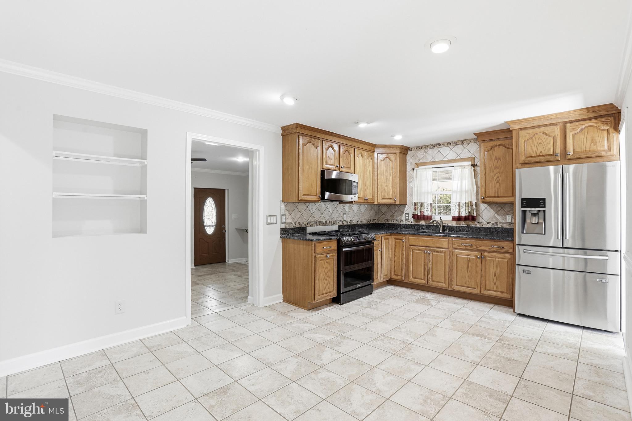 8324 Newland Road Warsaw, VA 22572 - Photo 8 of 31 a kitchen with granite countertop a refrigerator and a stove top oven
