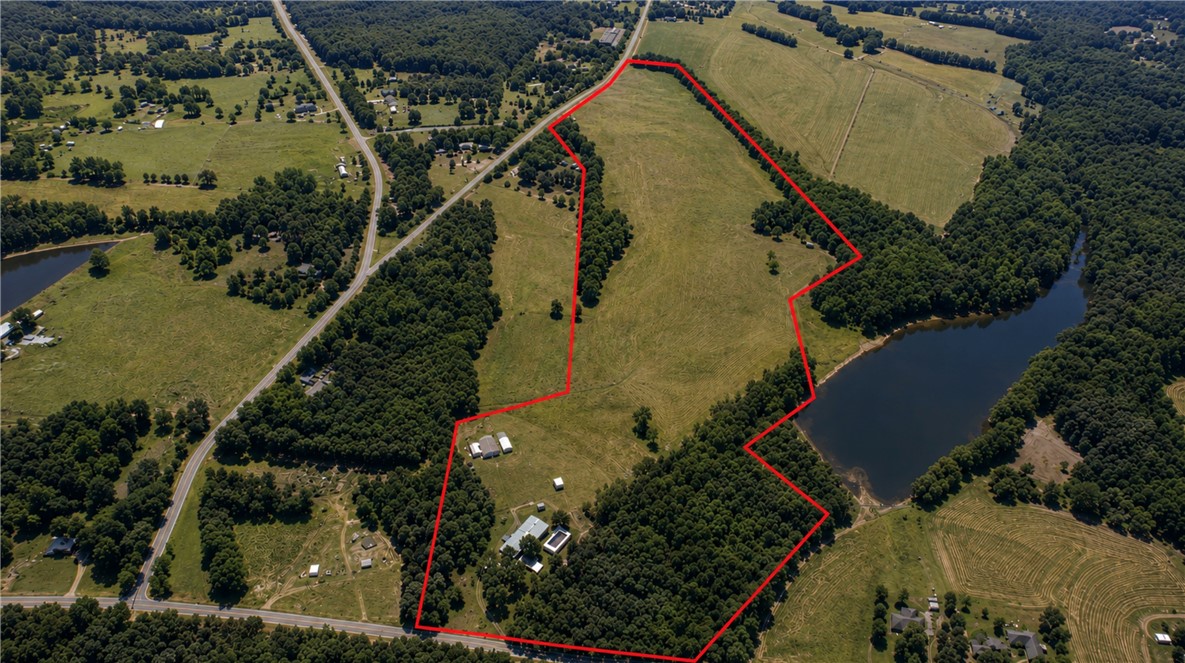 911 State Rd S-4-203 Belton, SC 29627 - Photo 3 of 49 A sweeping aerial perspective reveals a vast parcel of land, featuring verdant fields, dense woodlands, and a private lake.