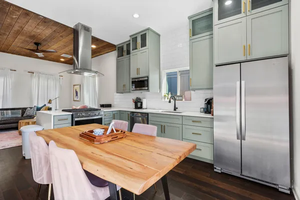 a kitchen with stainless steel appliances granite countertop a refrigerator a sink a stove and white cabinets with wooden floor