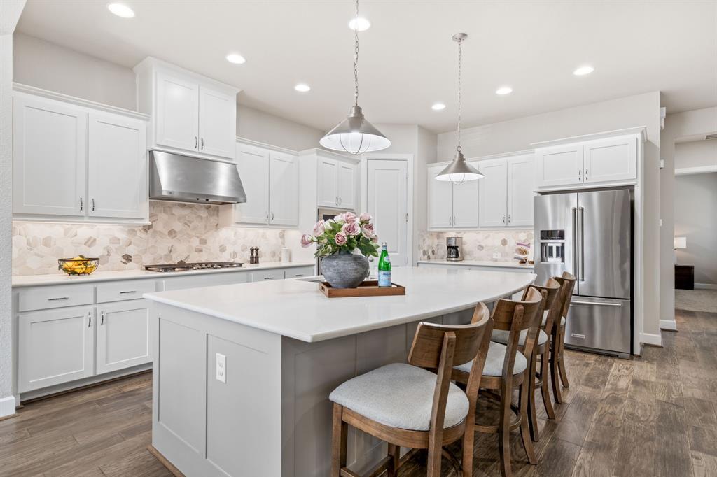 16548 Indiangrass Road Frisco, TX 75033 - Photo 3 of 39 a kitchen with stainless steel appliances kitchen island granite countertop a dining table chairs and white cabinets
