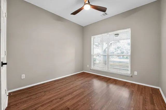 a view of an empty room with wooden floor fireplace and a window
