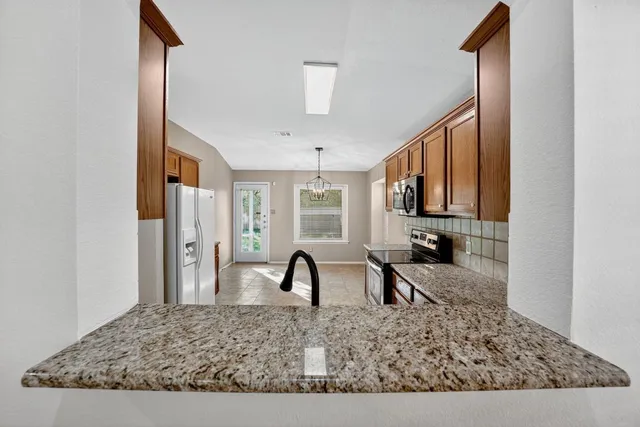 a kitchen with stainless steel appliances granite countertop a stove a sink dishwasher a refrigerator and a microwave