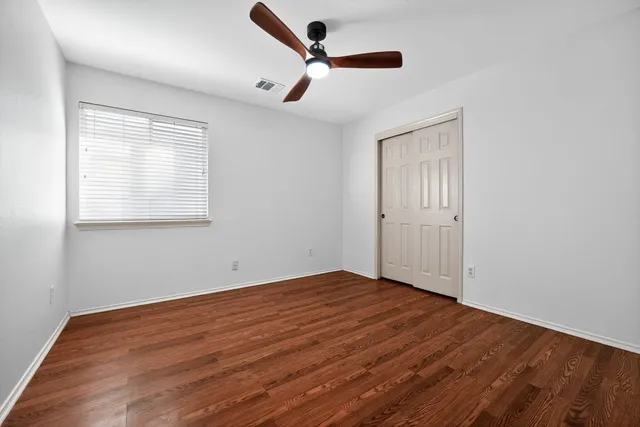 a view of empty room with wooden floor and fan
