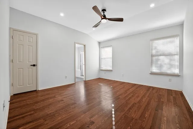 an empty room with wooden floor cabinet and windows