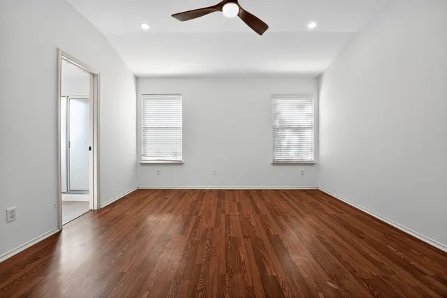 a view of empty room with wooden floor and ceiling fan