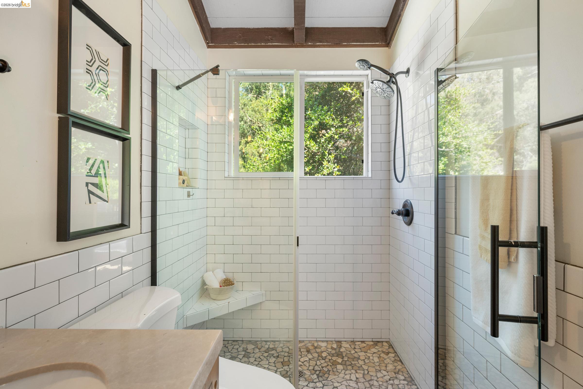 6600 Heather Ridge Way Oakland, CA 94611 - Photo 46 of 66 Walk-in shower featuring subway tile, a pebble floor, and a built-in shower bench