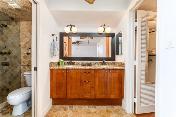a bathroom with a granite countertop toilet and a sink