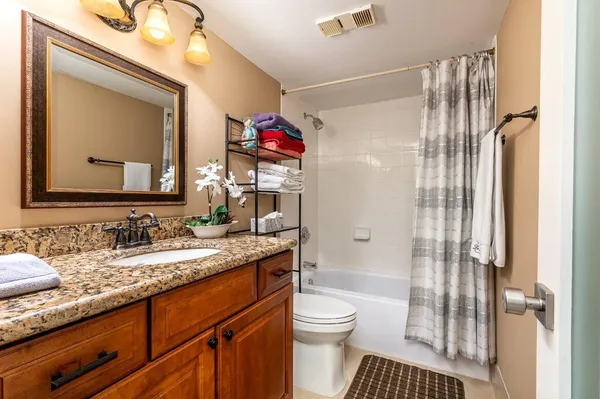 a bathroom with a granite countertop sink mirror vanity and toilet