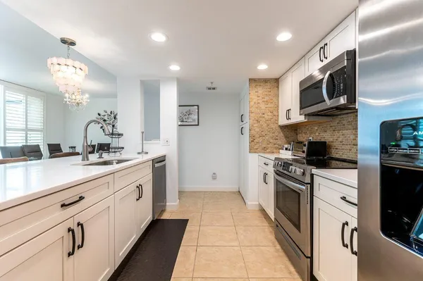 a large kitchen with stainless steel appliances granite countertop a large stove a sink dishwasher and a microwave oven with white cabinets