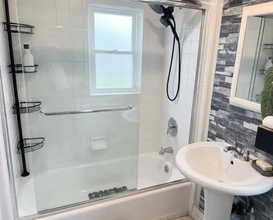 a bathroom with a bath tub sink shower and mirror