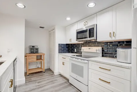 a kitchen with white cabinets and appliances