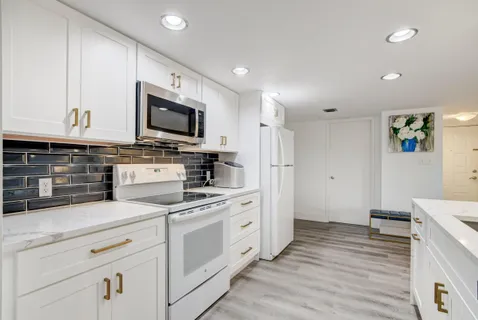 a kitchen with stainless steel appliances white cabinets and stove top oven