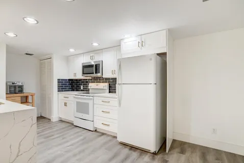 a kitchen with cabinets stainless steel appliances and wooden floor