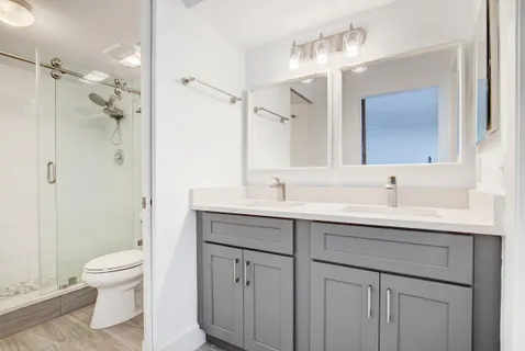 a bathroom with a toilet a sink a mirror and a shower