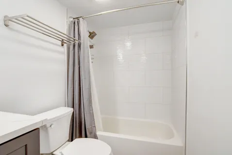 a bathroom with a shower a toilet and a tub