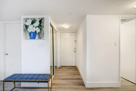 a view of a hallway with wooden floor and closet