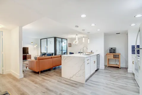 a large room with kitchen island a sink wooden floor and living room view